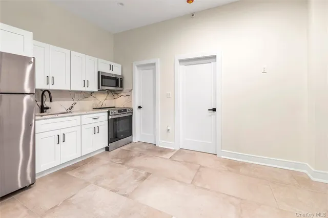 a kitchen with white cabinets stainless steel appliances and a refrigerator