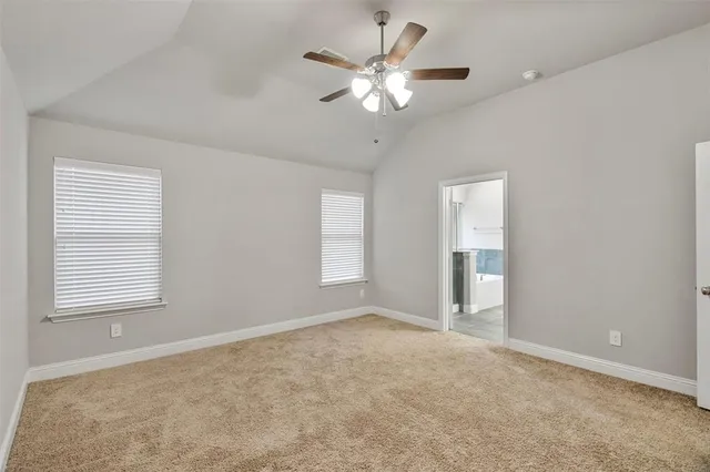 an empty room with chandelier fan and windows