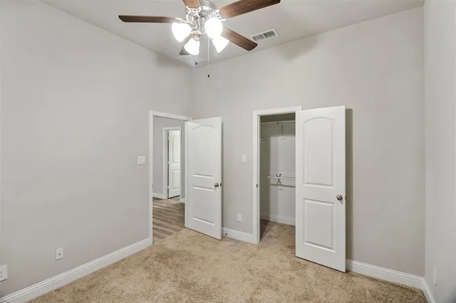 an empty room with closet and a chandelier fan