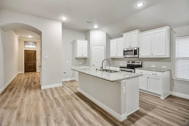 a kitchen with kitchen island granite countertop a sink cabinets and stainless steel appliances