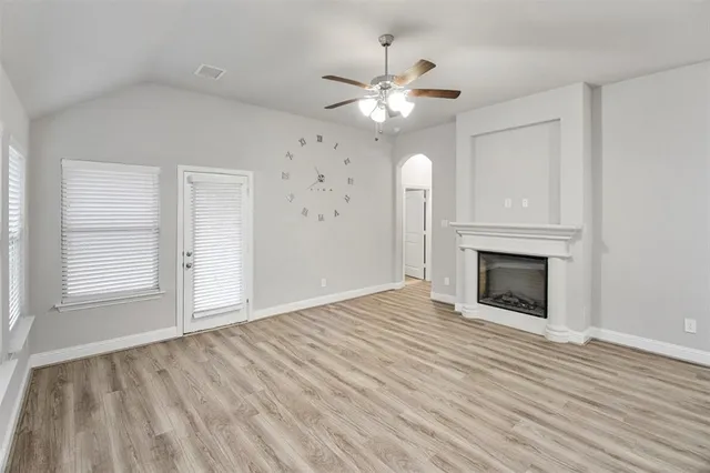 a view of an empty room with wooden floor fireplace and a window