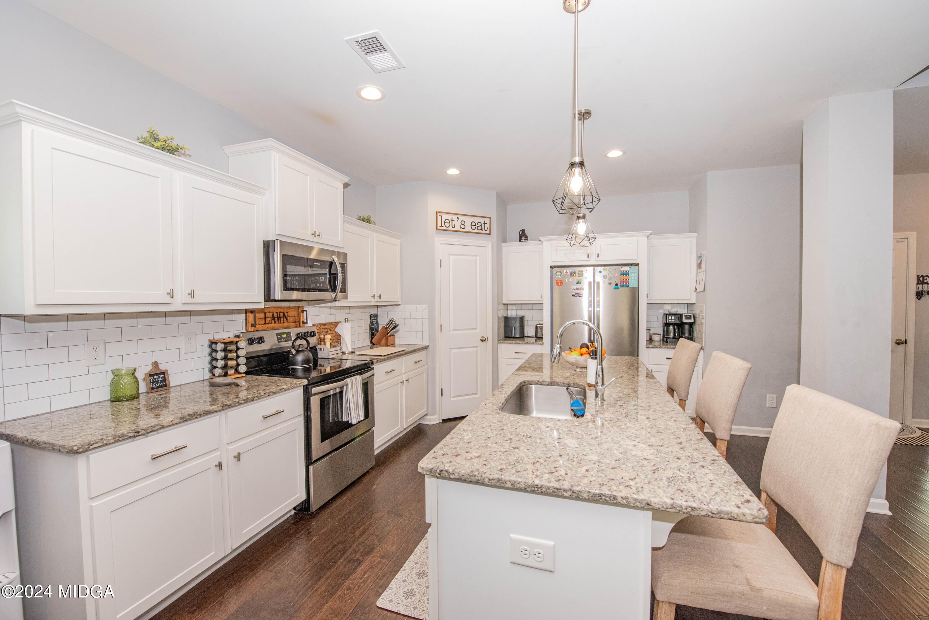 103 Wax Myrtle Way Perry, GA 31069 - Photo 16 of 62 a open kitchen with stainless steel appliances kitchen island granite countertop a kitchen island hardwood floor sink and stove