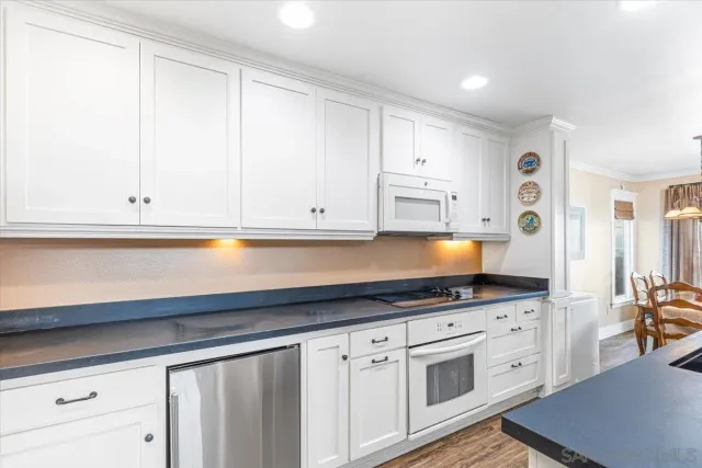 a kitchen with granite countertop white cabinets and white appliances