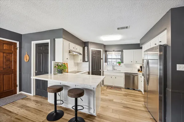 a kitchen with stainless steel appliances granite countertop a refrigerator and a stove top oven
