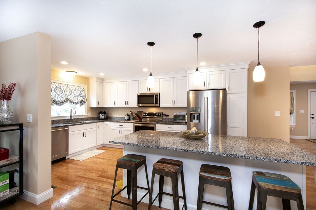 4 Kevin's Way, Unit 4 Scituate, MA 02066 - Photo 11 of 26 a kitchen with stainless steel appliances granite countertop a sink a stove a refrigerator a center island with a dining table and chairs