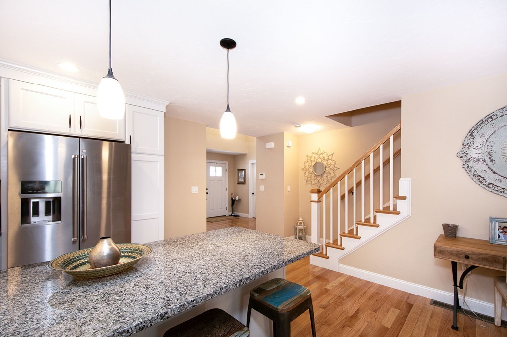 4 Kevin's Way, Unit 4 Scituate, MA 02066 - Photo 14 of 26 a kitchen with stainless steel appliances kitchen island granite countertop a table chairs and a wooden floors