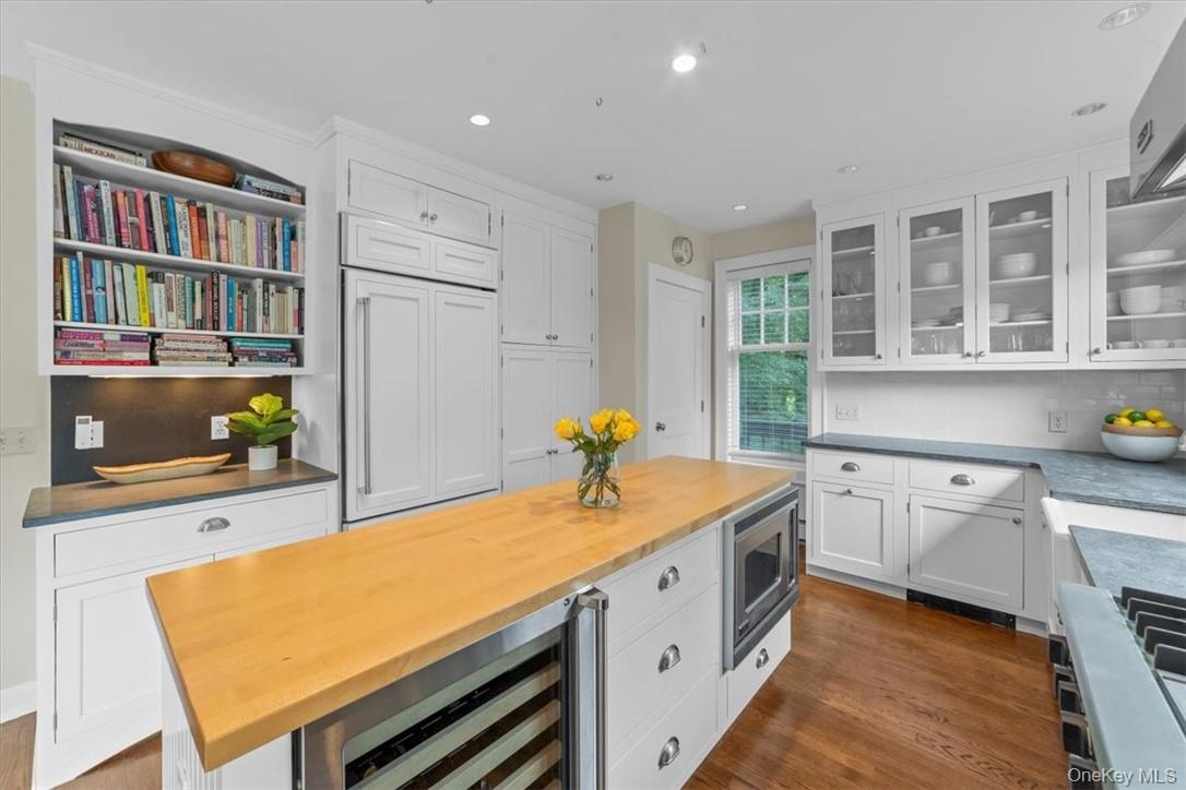 28 Inningwood Road Ossining, NY 10562 - Photo 18 of 37 Kitchen with white cabinetry, stainless steel microwave, beverage cooler, backsplash, and dark wood-type flooring