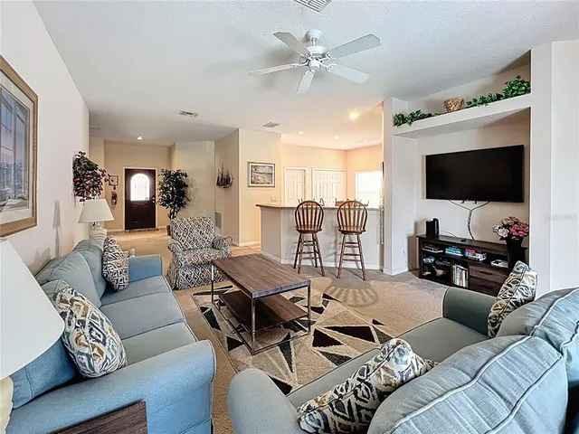 a living room with furniture a ceiling fan and a flat screen tv