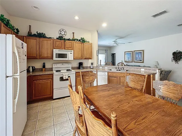 a kitchen with a stove a sink dishwasher a refrigerator with a dining table and chairs