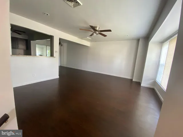 an empty room with wooden floor fan and windows