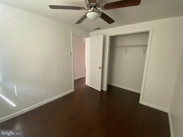 a view of an empty room with closet and a ceiling fan