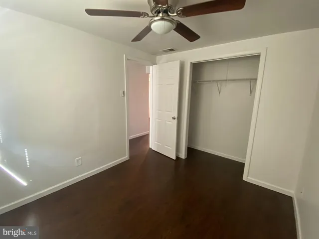 a view of an empty room with closet and a ceiling fan