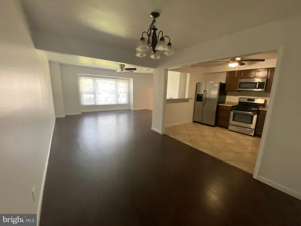 an empty room with wooden floor fireplace and windows