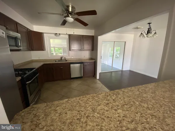 a kitchen with kitchen island granite countertop a sink a counter top space appliances and cabinets
