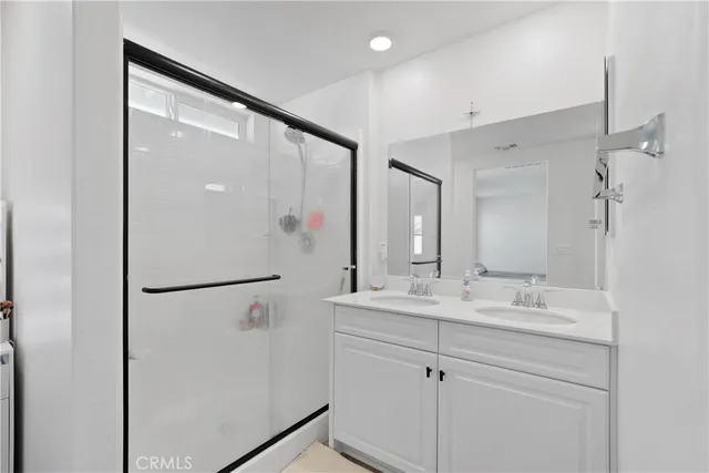 a bathroom with a double vanity sink mirror and shower