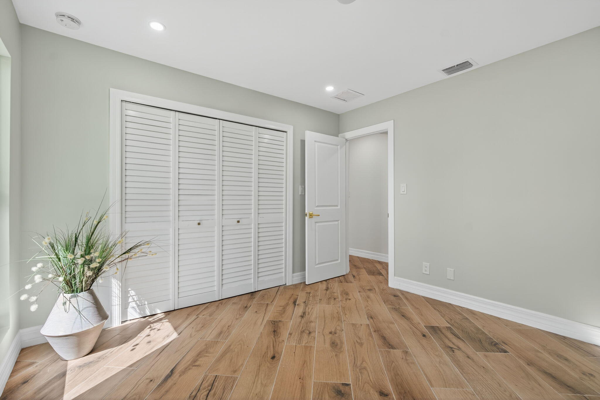 5273 Southeast Tall Pines Way Stuart, FL 34997 - Photo 37 of 62 an empty room with wooden floor and a potted plant