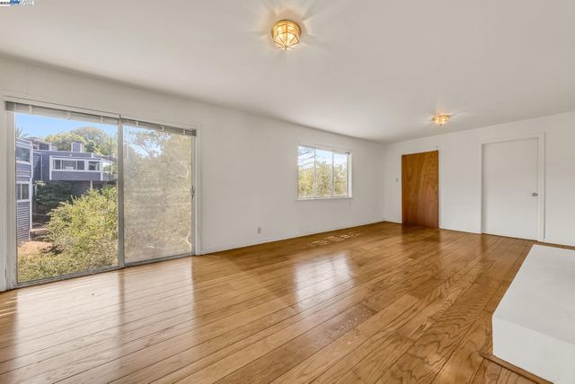 a view of an empty room with window and wooden floor