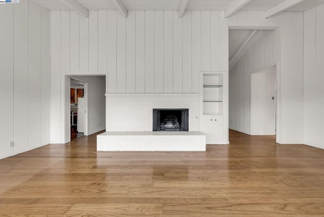 a view of empty room with wooden floor and fireplace