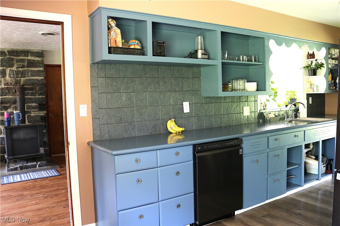 14485 Bass Lake Road Newbury, OH 44065 - Photo 11 of 22 Kitchen with open shelves, dishwasher, dark wood-type flooring, decorative backsplash, and a wood stove
