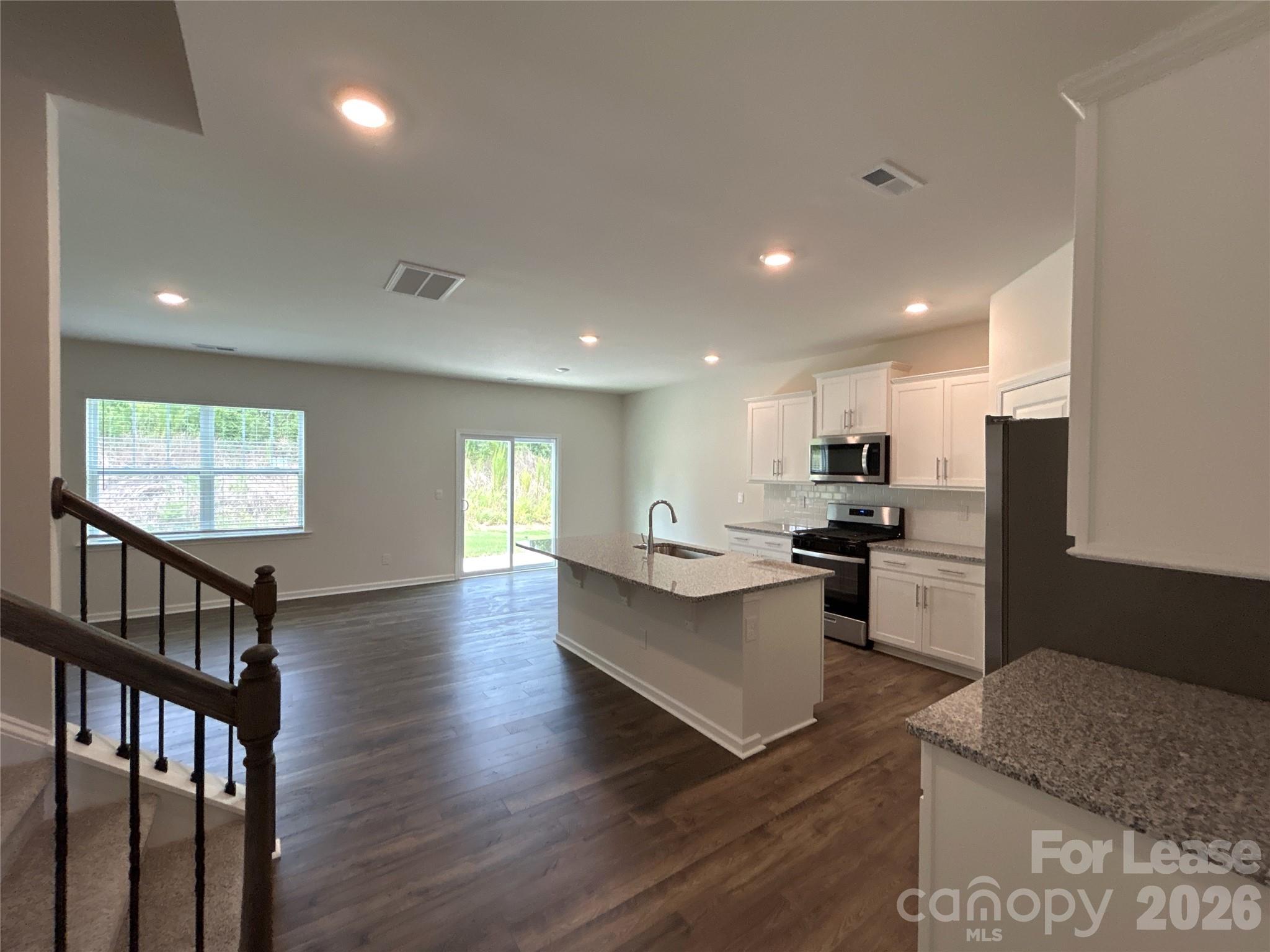 1920 Vanderlyn Street Monroe, NC 28112 - Photo 4 of 24 a kitchen with stainless steel appliances kitchen island granite countertop a stove a refrigerator a microwave a dining table and chairs with wooden floor