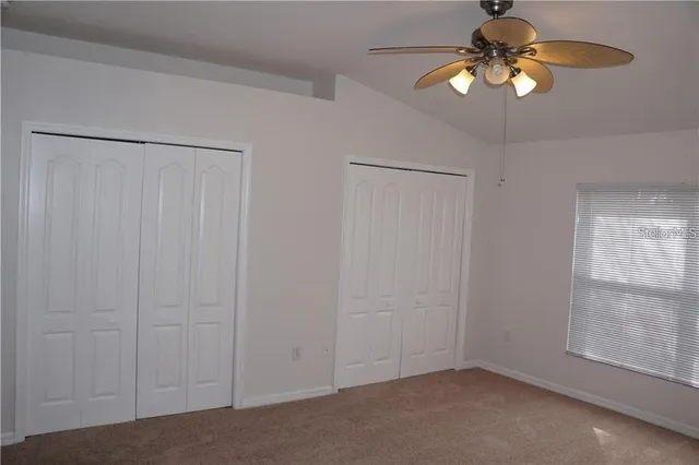 an empty room with closet and a chandelier fan