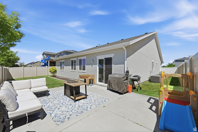 1175 Silver Hollow Road Syracuse, UT 84075 - Photo 32 of 34 Rear exterior featuring a concrete patio, sliding glass door, multiple windows, and a fenced backyard with a grass lawn