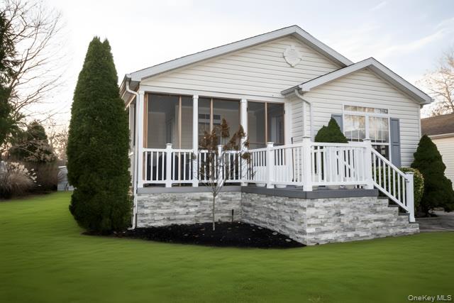 Back of house with a sunroom, a lawn, and a wooden deck