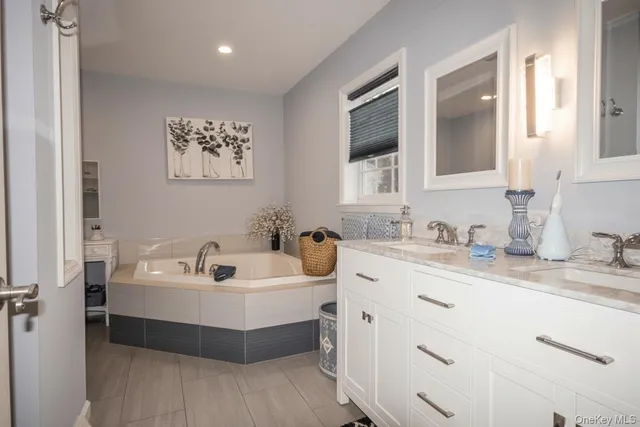 a bathroom with a double vanity sink mirror and bathtub