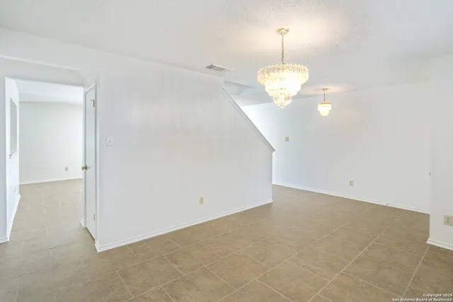 a view of an empty room with a chandelier fan
