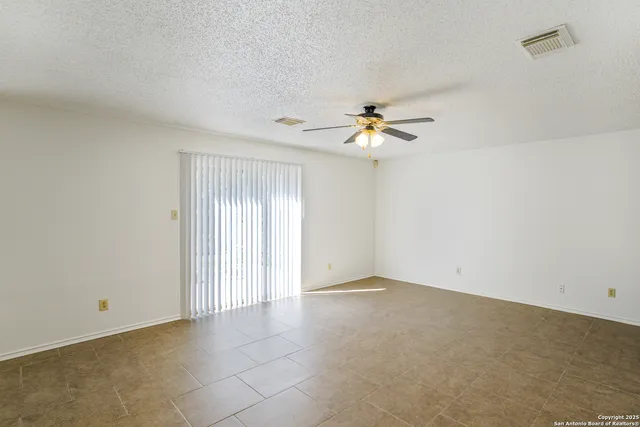 an empty room with fan and windows