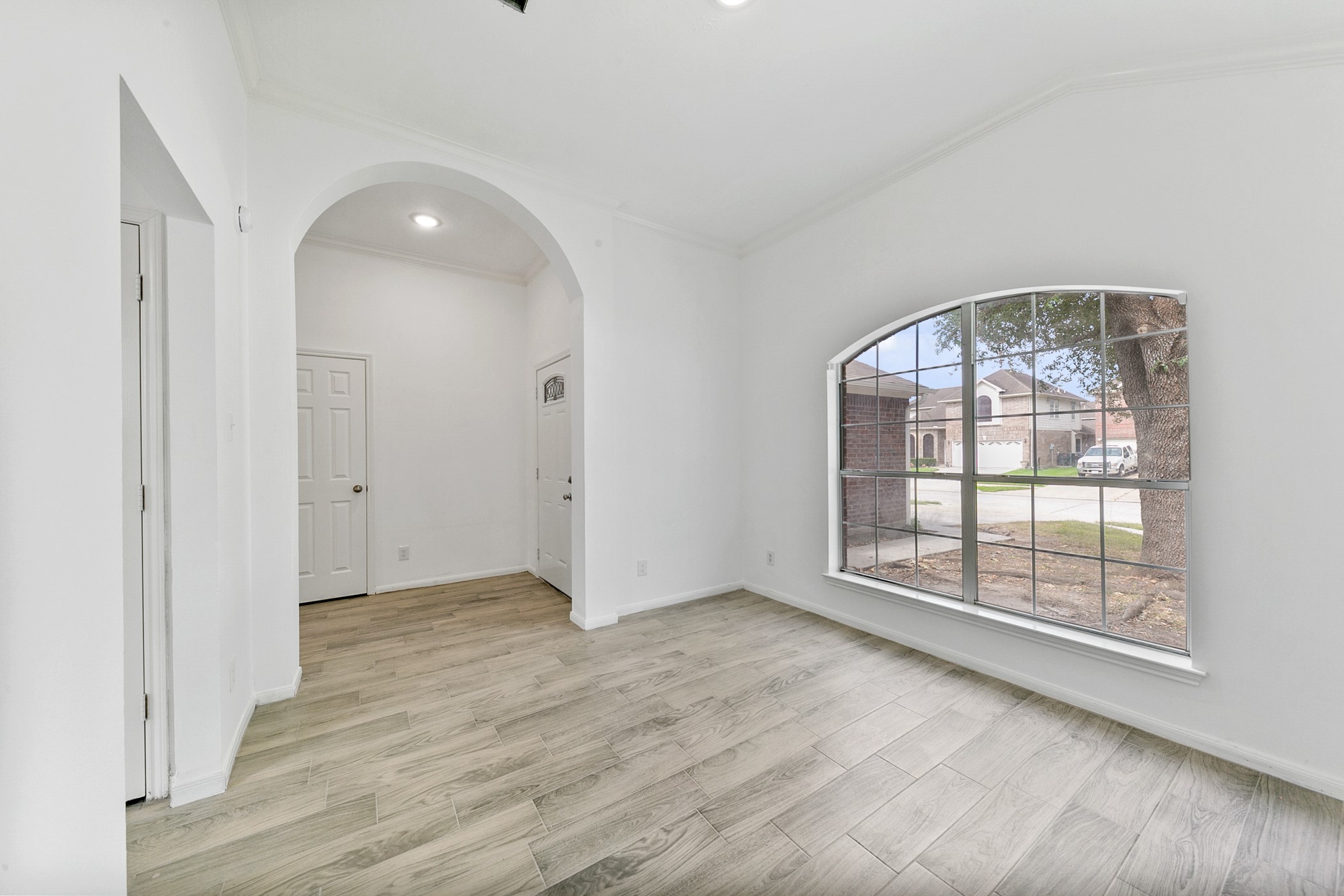12014 Raven View Drive Houston, TX 77067 - Photo 2 of 29 Bright and inviting entryway with wood-look flooring, white walls, and a large arched window offering a view of the front yard. The space features an elegant arch leading to the main living area.