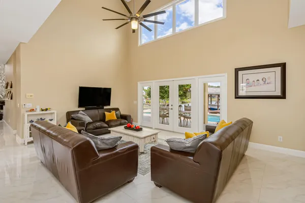 a living room with furniture floor to ceiling window and a flat screen tv