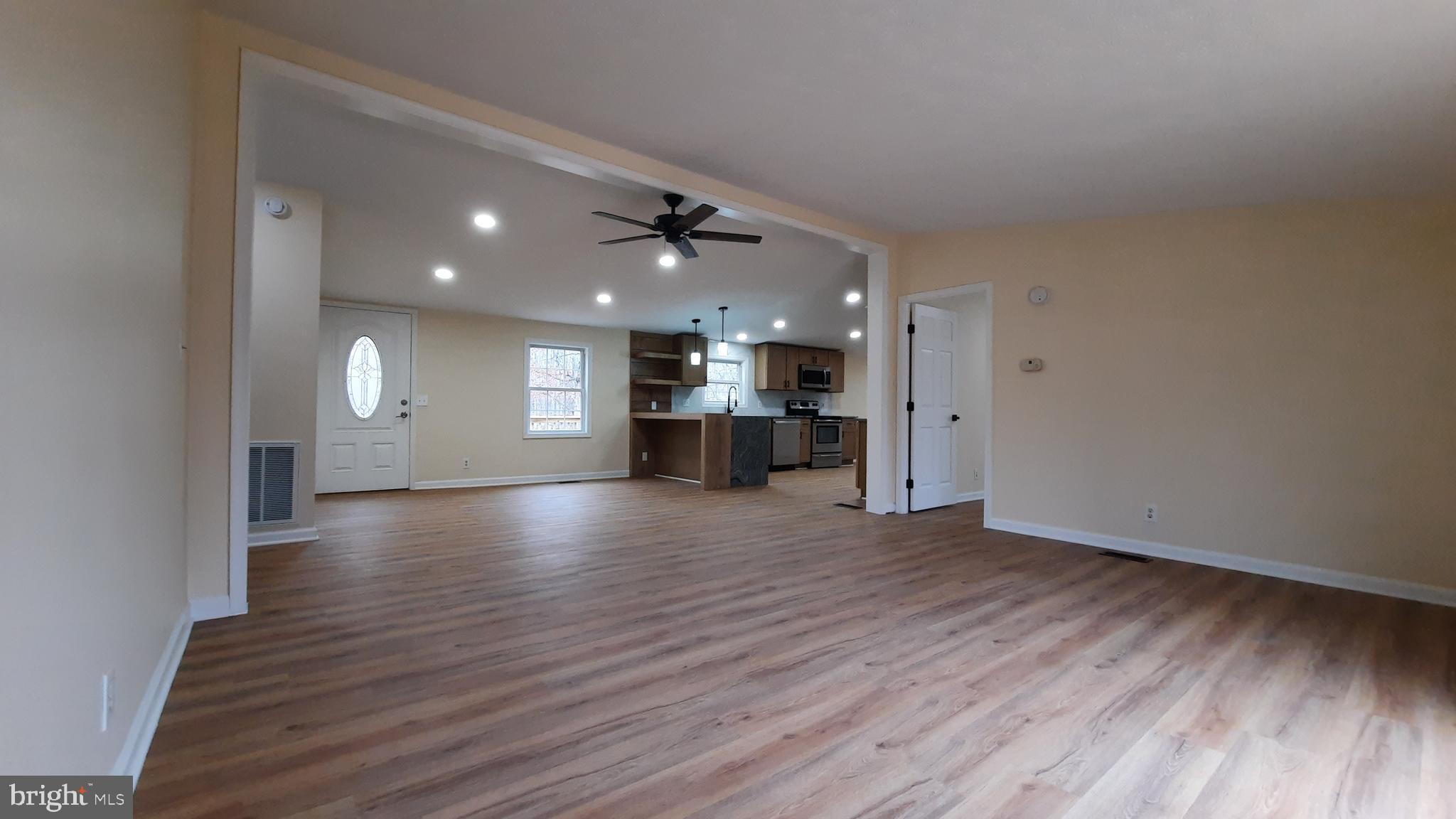 21051 Seigen Lane Richardsville, VA 22736 - Photo 5 of 42 a view of an empty room with wooden floor kitchen view and a window