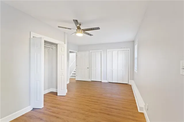 a view of empty room with wooden floor and fan