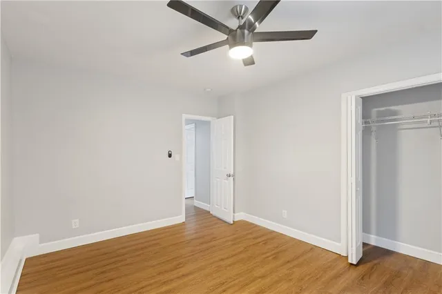 an empty room with wooden floor fan and windows