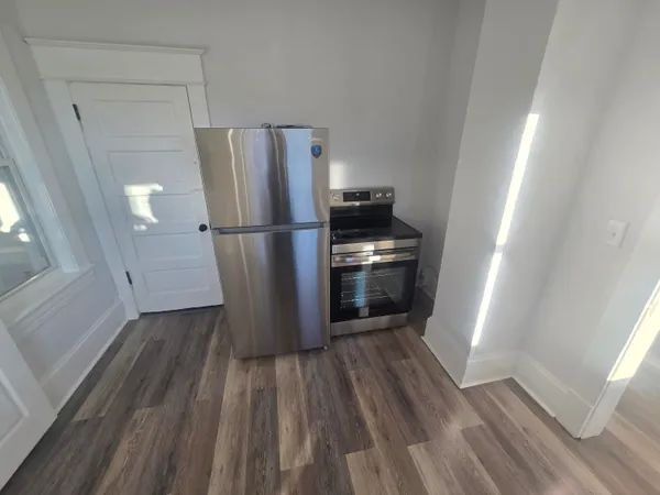 a kitchen with a refrigerator and wooden floor