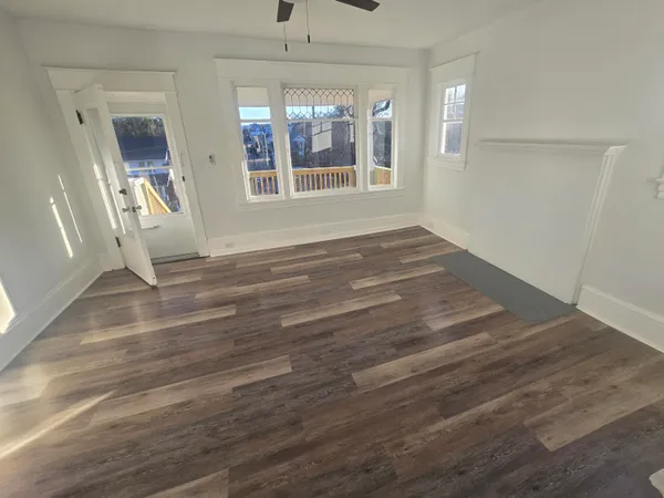 an empty room with wooden floor and windows