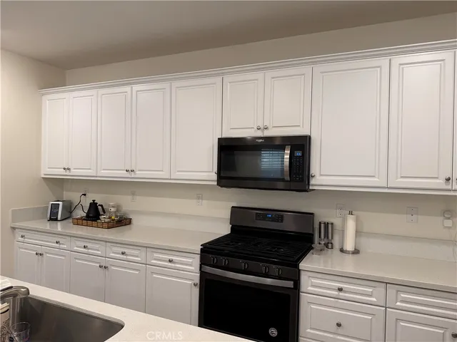 a kitchen with white cabinets and black appliances