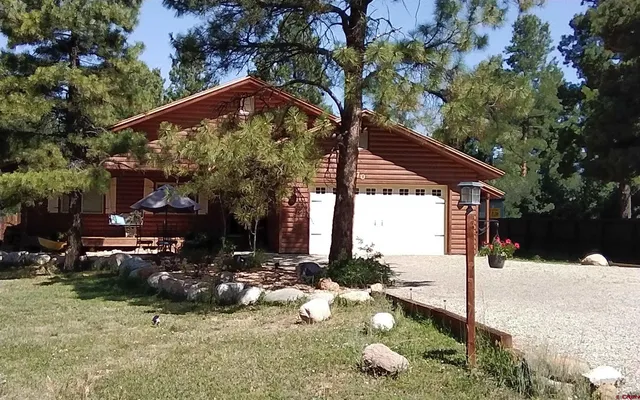 a backyard of a house with table and chairs under an umbrella