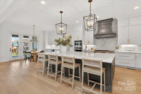 a kitchen with stainless steel appliances granite countertop a dining table chairs stove and white cabinets