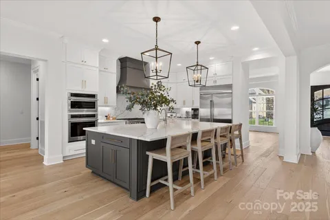 a kitchen with stainless steel appliances kitchen island granite countertop a wooden floor and white cabinets