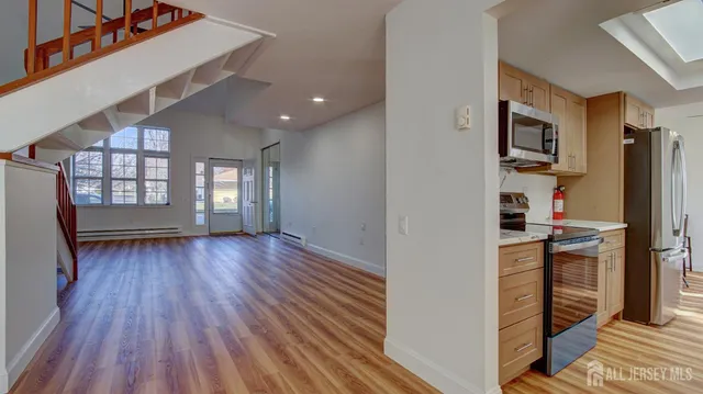 a view of a kitchen and an empty room with a window