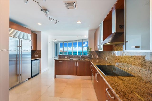 a kitchen with stainless steel appliances granite countertop a sink and a refrigerator
