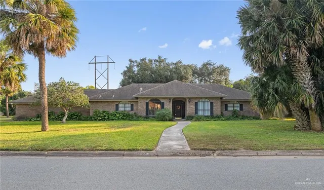 a view of a house with a big yard and palm trees