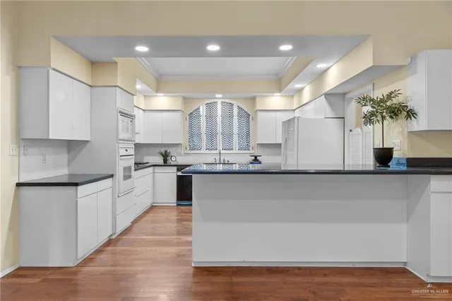 a large kitchen with granite countertop a large counter top a sink stainless steel appliances and cabinets