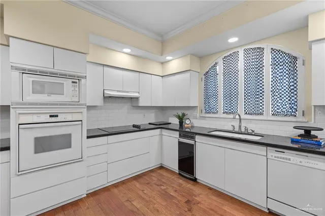 a kitchen with granite countertop white cabinets and white appliances