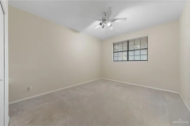 an empty room with windows and chandelier fan