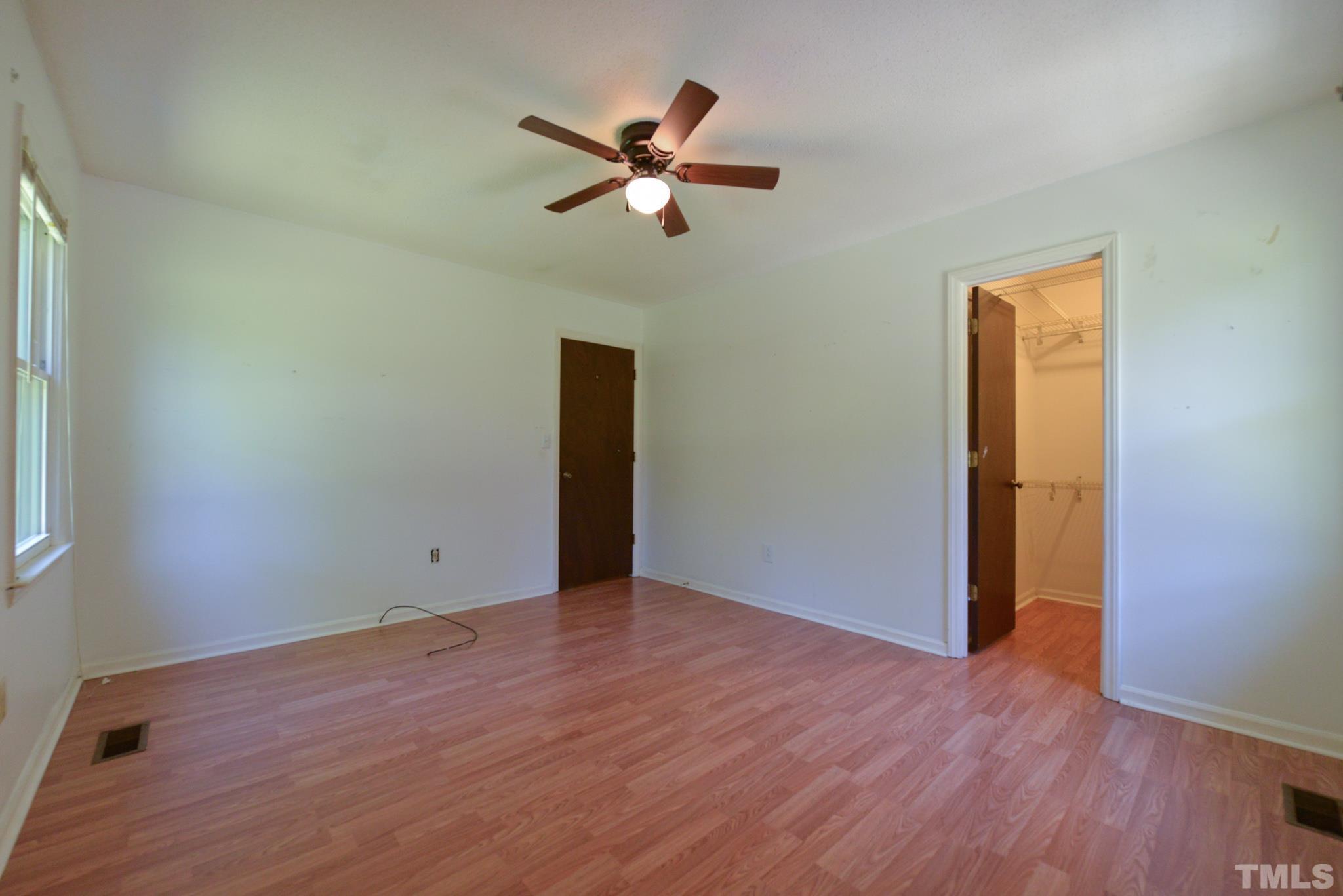 119 Mt Pleasant Road Willow Spring, NC 27592 - Photo 14 of 22 an empty room with wooden floor a ceiling fan and windows