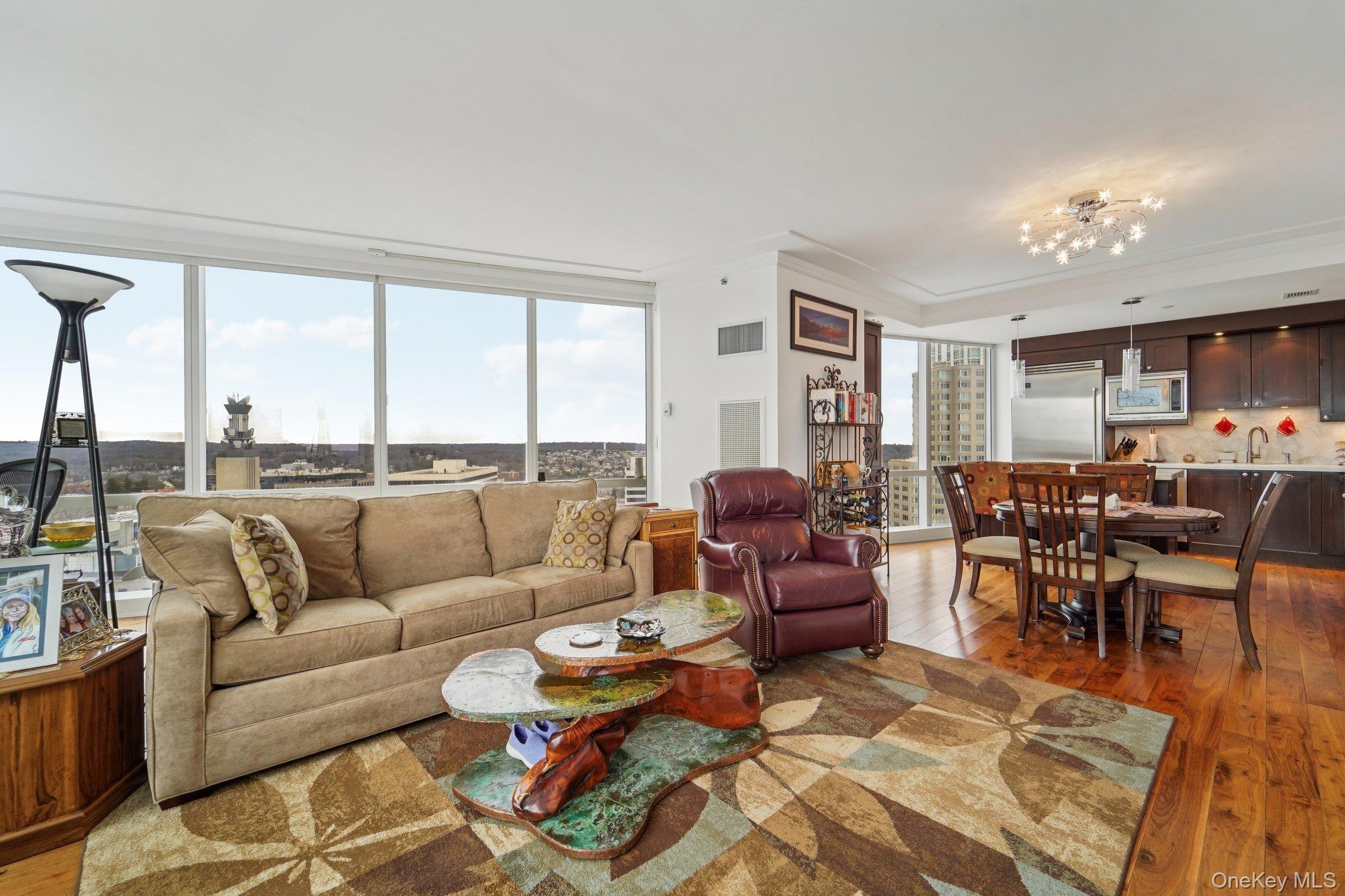 1 Renaissance Square, Unit 25G White Plains, NY 10601 - Photo 2 of 23 a living room with furniture potted plant kitchen view and large windows