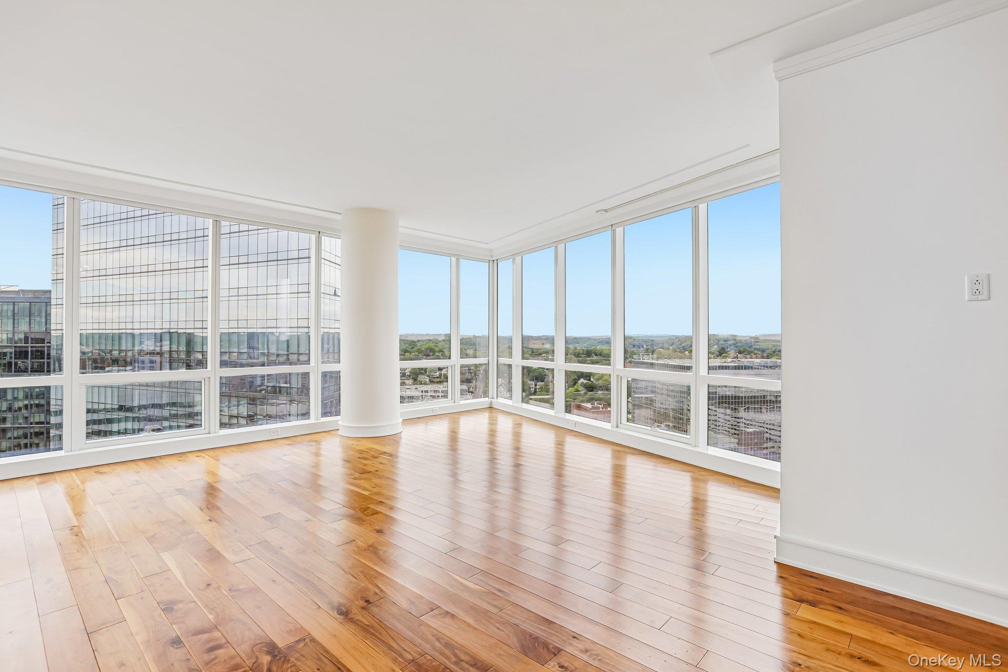 1 Renaissance Square, Unit 25G White Plains, NY 10601 - Photo 2 of 22 Expansive room featuring floor-to-ceiling windows, wood-finish flooring, white walls, and elegant crown molding